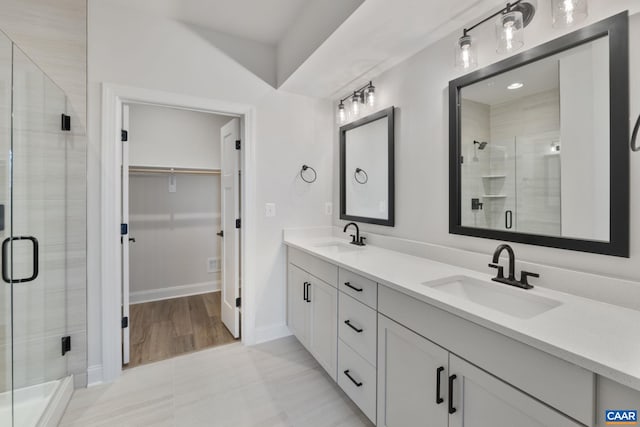 full bathroom with a sink, double vanity, a stall shower, and a spacious closet