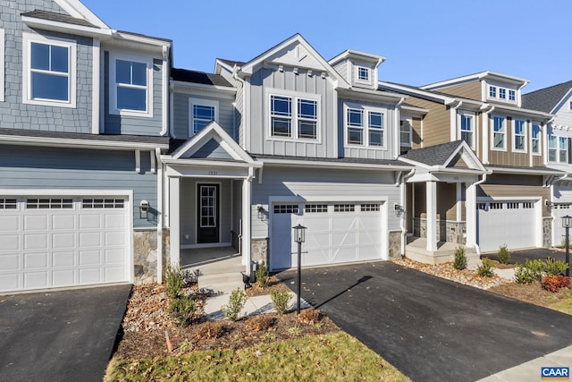 multi unit property with aphalt driveway, stone siding, board and batten siding, and a garage