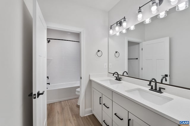 full bath featuring double vanity, toilet, wood finished floors, and a sink