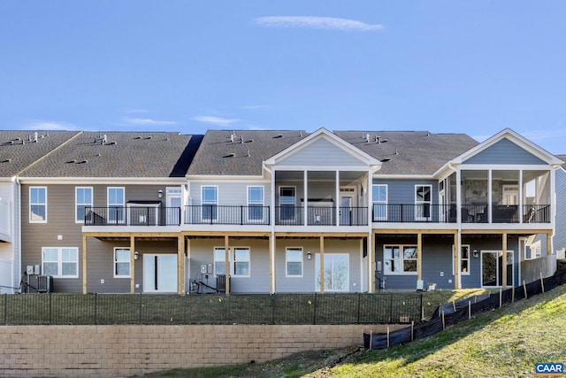 rear view of property with roof with shingles, a fenced backyard, and a sunroom