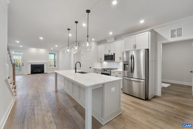 kitchen with a center island with sink, visible vents, stainless steel appliances, crown molding, and backsplash