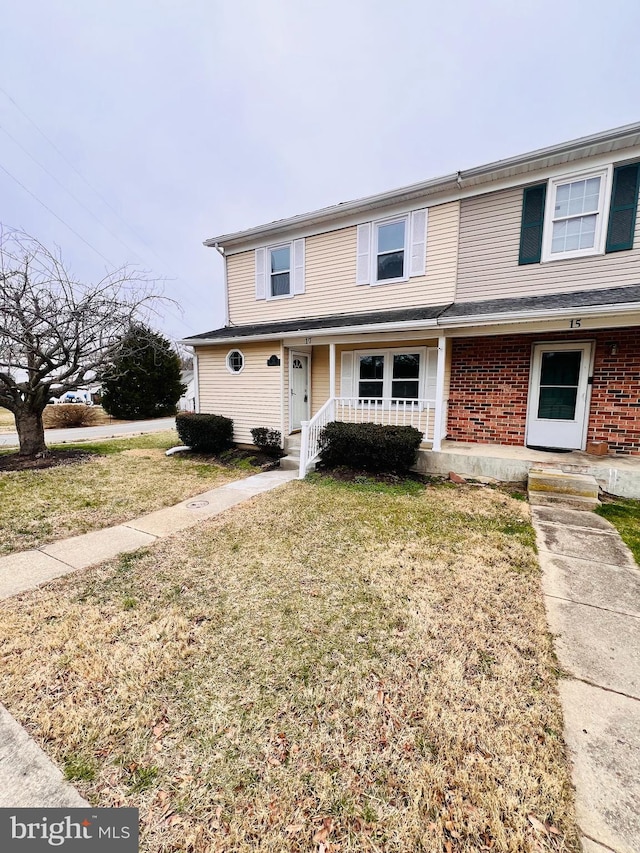 townhome / multi-family property featuring brick siding, a porch, and a front lawn