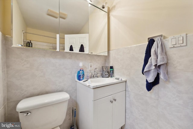 bathroom with toilet, vanity, and tile walls