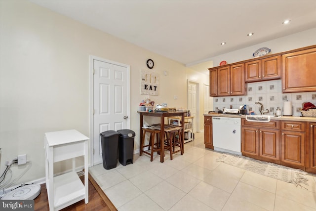 kitchen featuring brown cabinetry, decorative backsplash, a sink, and white dishwasher