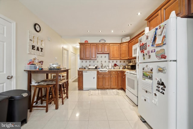 kitchen with decorative backsplash, brown cabinets, recessed lighting, light tile patterned flooring, and white appliances