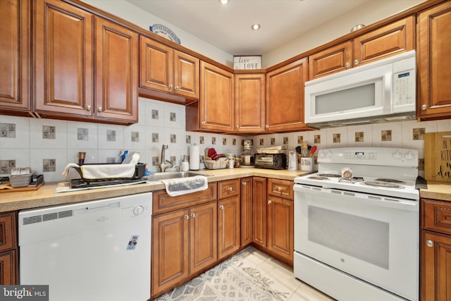 kitchen featuring white appliances, brown cabinets, and a sink