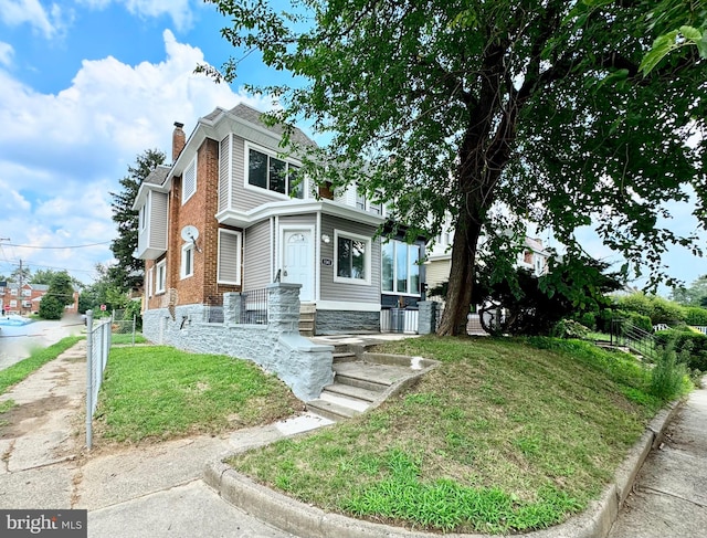 view of front of house with a front lawn, a chimney, and fence