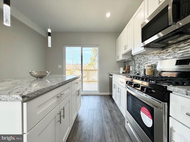 kitchen with tasteful backsplash, appliances with stainless steel finishes, white cabinets, and dark wood finished floors