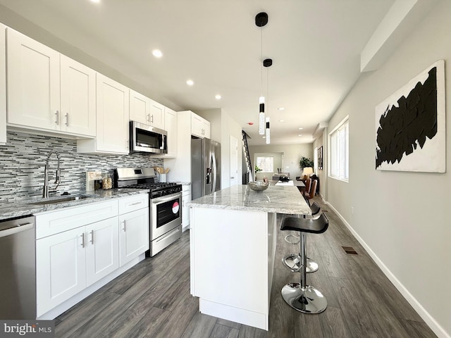 kitchen with tasteful backsplash, a center island, white cabinets, stainless steel appliances, and a sink