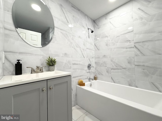 bathroom featuring vanity, tile walls, marble finish floor, and shower / bathtub combination