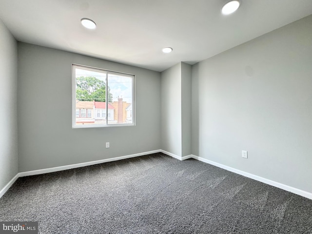 spare room featuring recessed lighting, dark carpet, and baseboards