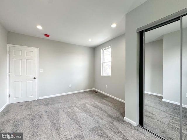 unfurnished bedroom featuring a closet, recessed lighting, baseboards, and carpet floors