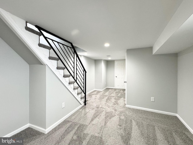 finished basement with baseboards, stairs, and carpet