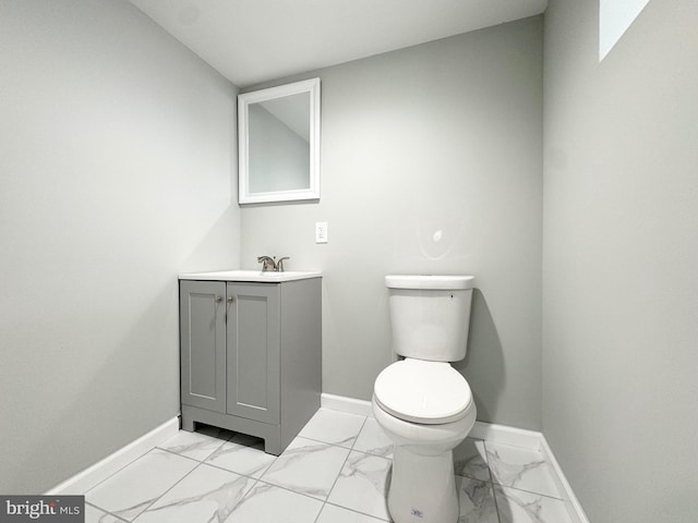 bathroom with marble finish floor, toilet, vanity, and baseboards