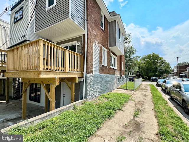 view of side of home with brick siding and a wooden deck