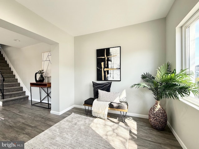 living area with stairway, dark wood-type flooring, and baseboards