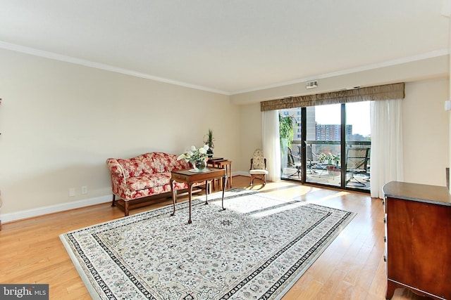 living area featuring light wood-type flooring, baseboards, and crown molding