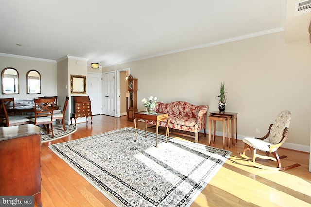 living area featuring visible vents, ornamental molding, baseboards, and wood finished floors