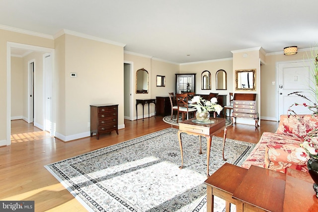 living area featuring baseboards, wood finished floors, and crown molding