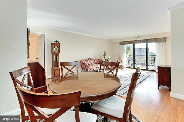 dining space with baseboards, light wood-style flooring, and ornamental molding