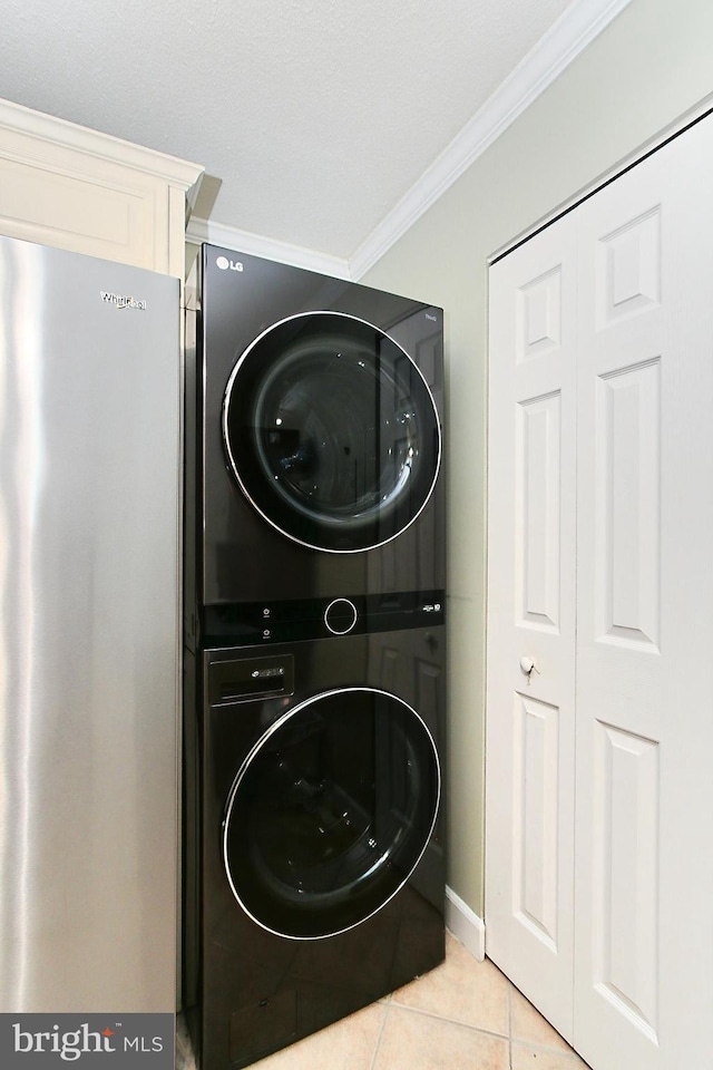 laundry area featuring laundry area, light tile patterned floors, crown molding, and stacked washer and clothes dryer