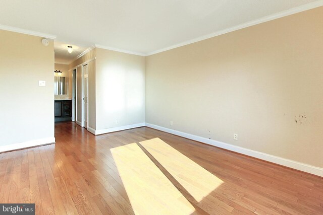 spare room with baseboards, wood finished floors, and ornamental molding