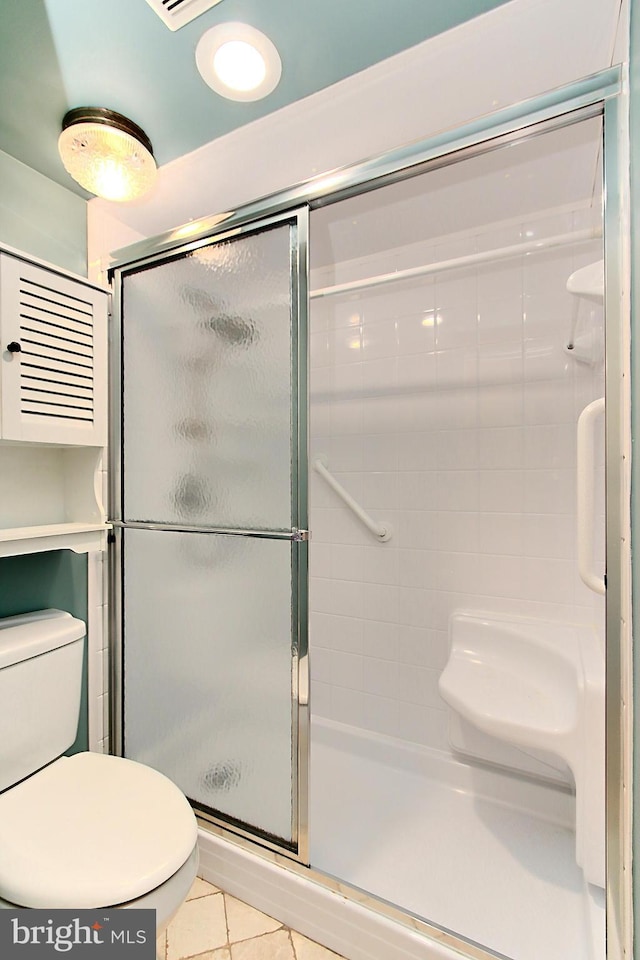 bathroom with tile patterned flooring, a shower stall, and toilet