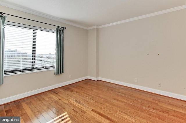 spare room with light wood-type flooring, baseboards, and ornamental molding