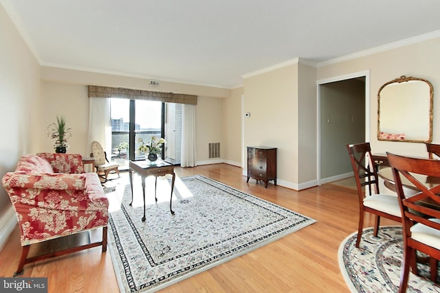 living area with visible vents, wood finished floors, and ornamental molding