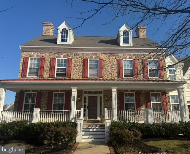 view of front facade with covered porch and a chimney