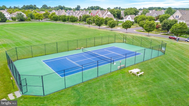 view of sport court with a residential view, a lawn, and fence