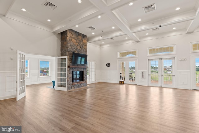 unfurnished living room with visible vents, a decorative wall, beamed ceiling, and french doors