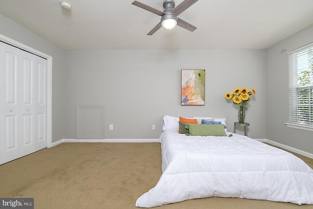 bedroom with a closet, baseboards, a ceiling fan, and carpet flooring