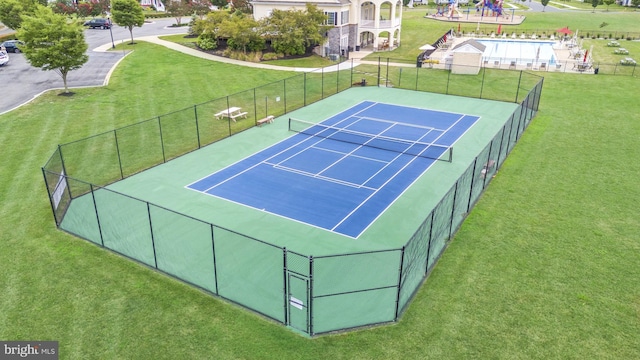 view of sport court with a lawn and fence