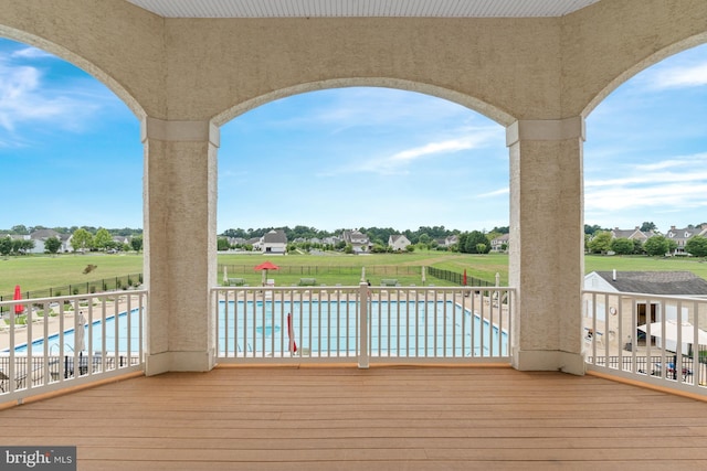 wooden deck featuring a community pool, fence, and a yard