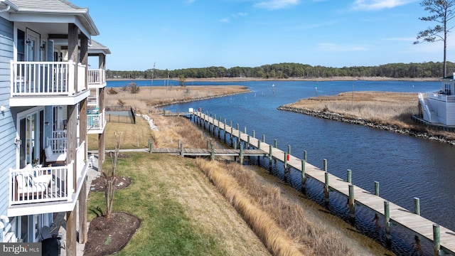 view of dock with a lawn and a water view