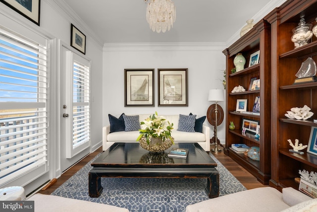 living area with an inviting chandelier, crown molding, baseboards, and dark wood-type flooring