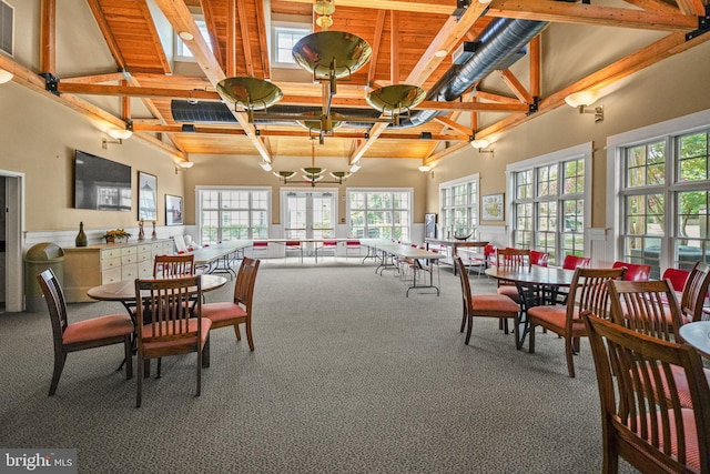 dining room with a wainscoted wall, beam ceiling, carpet, and a high ceiling