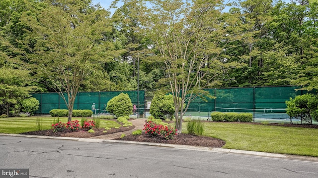 surrounding community featuring a lawn, a tennis court, and fence