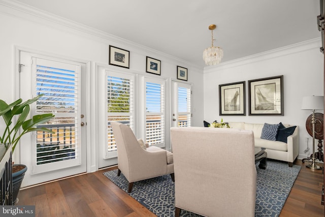 living room with a chandelier, ornamental molding, and wood finished floors