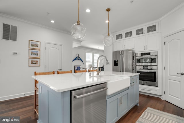 kitchen featuring a center island with sink, visible vents, a sink, appliances with stainless steel finishes, and crown molding