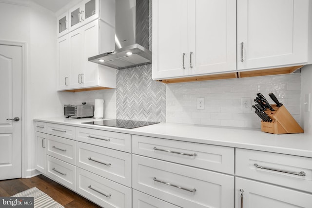 kitchen with dark wood finished floors, light countertops, white cabinetry, wall chimney range hood, and black electric cooktop