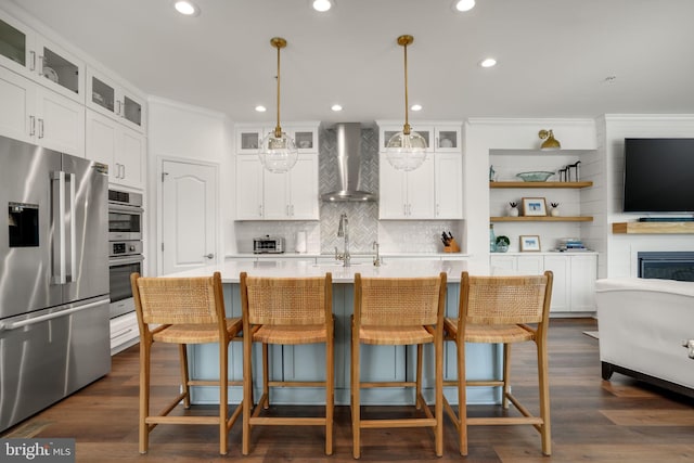 kitchen with light countertops, wall chimney range hood, dark wood-style floors, and appliances with stainless steel finishes