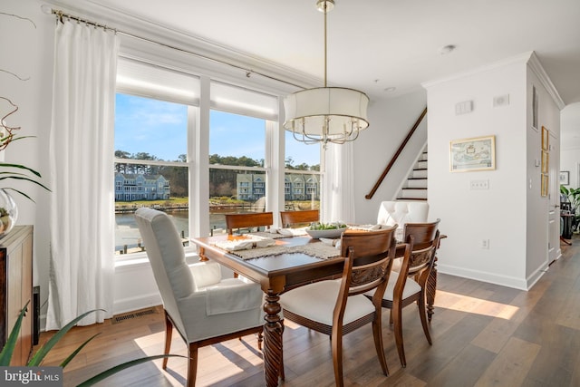 dining space featuring visible vents, an inviting chandelier, wood finished floors, and stairway