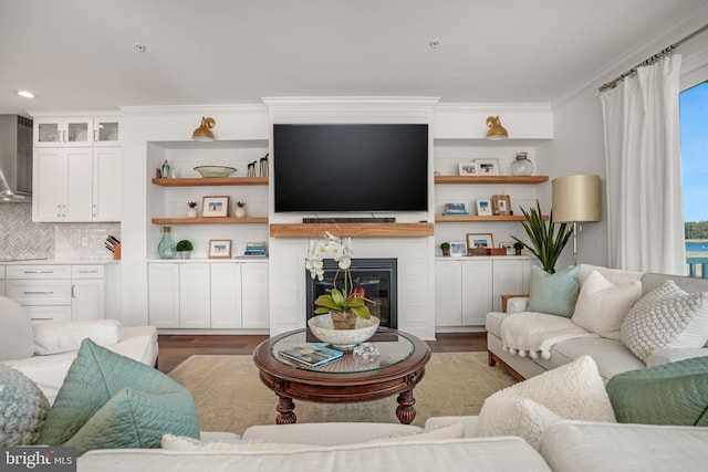 living room with a glass covered fireplace, crown molding, and wood finished floors