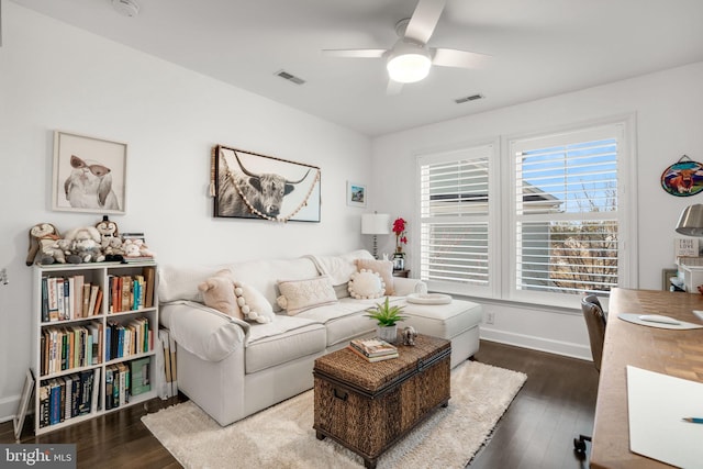 living area with dark wood finished floors, a ceiling fan, visible vents, and baseboards