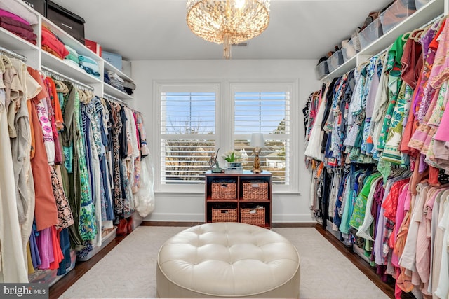 spacious closet featuring an inviting chandelier and wood finished floors