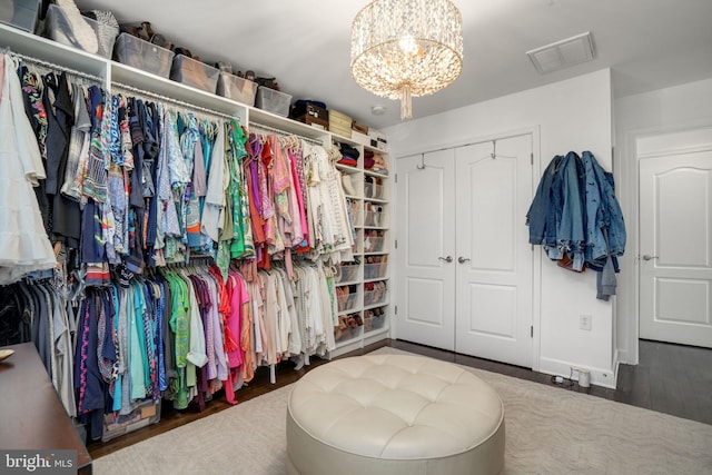 walk in closet with visible vents, wood finished floors, and a chandelier