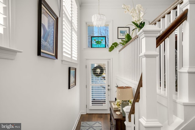 interior space featuring wood finished floors, baseboards, ornamental molding, a towering ceiling, and a chandelier