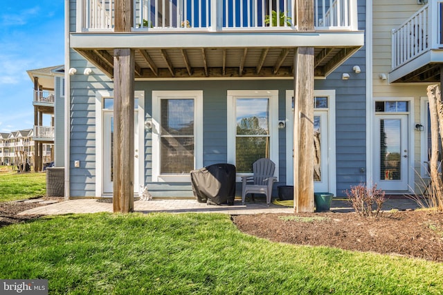 entrance to property featuring a patio and a lawn